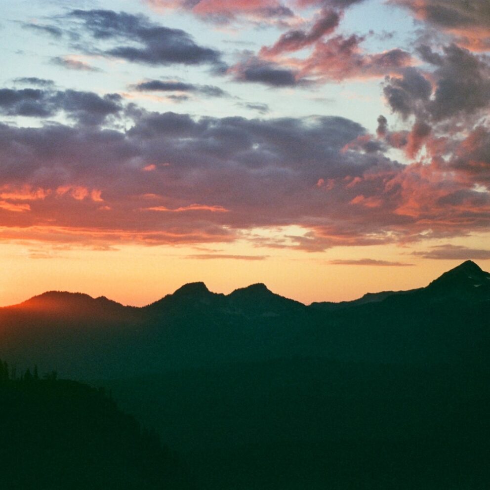 the sun is setting over a mountain range