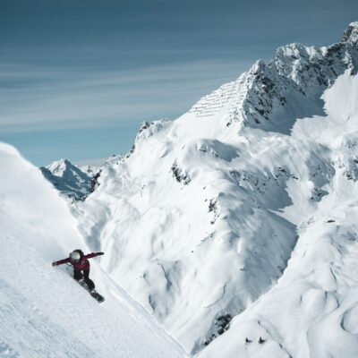 a person on a snowboard going down a snowy mountain