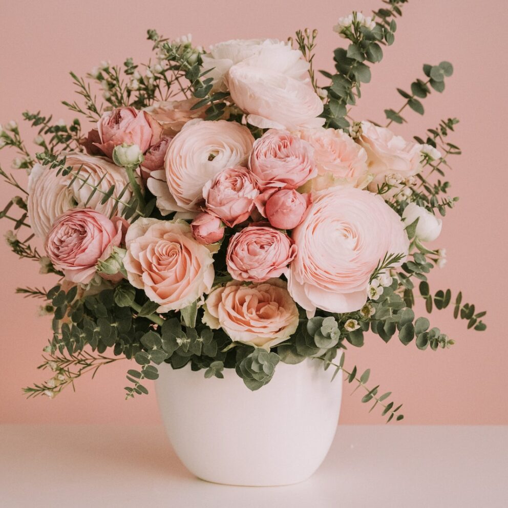 a white vase filled with lots of pink flowers