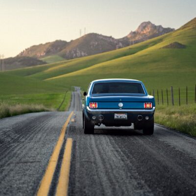 a blue pickup truck driving down a country road