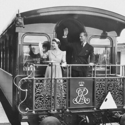 a black and white photo of people waving from a train