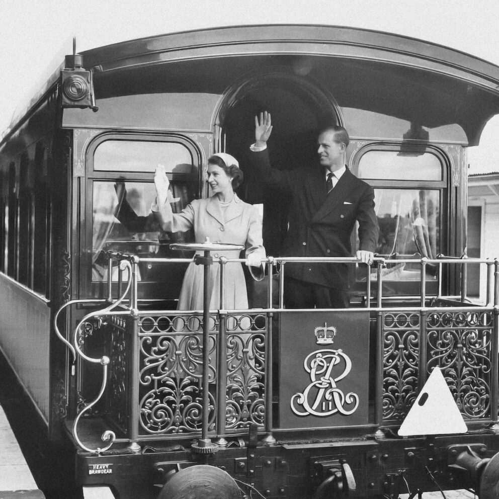 a black and white photo of people waving from a train