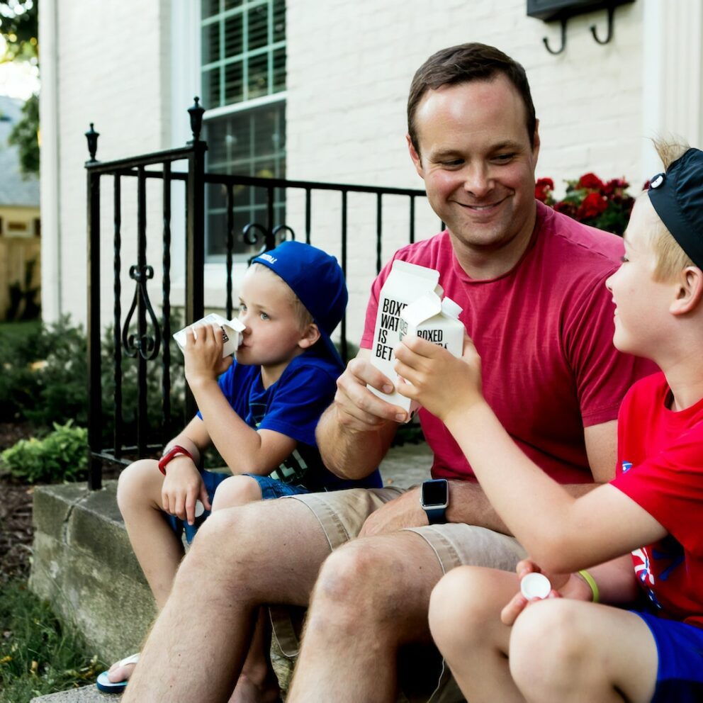 A father and his two boys enjoy drinking Boxed Water