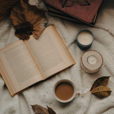an open book and two cups of coffee on a blanket
